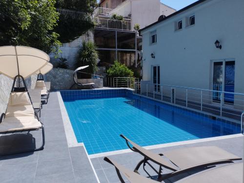 a swimming pool with chaise lounge chairs next to a building at Zoran Apartments in Sveti Stefan
