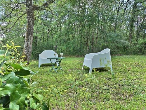 two white chairs and a table in the grass at Les gîtes de L'Isle Jourdain in Pujaudran