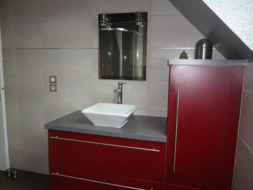 a bathroom with a sink and a red cabinet at Au gré des marées, 1 chambre. in Hanvec