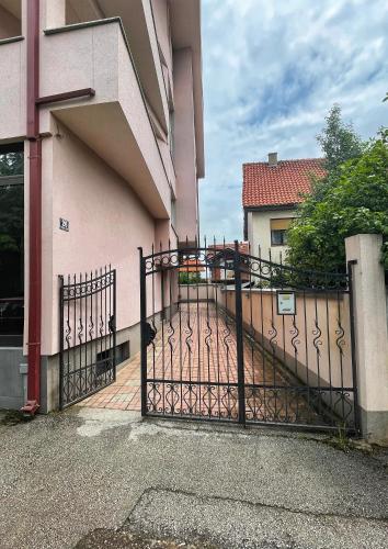 a black gate in front of a pink building at Apartman Cvetkovic in Vranje
