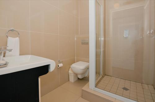 a bathroom with a shower and a toilet and a sink at Albatross Guest House Bantry Bay in Cape Town