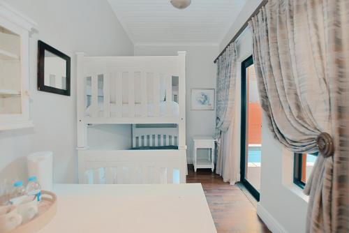 a white room with a bedroom with a bunk bed at Albatross Guest House Bantry Bay in Cape Town