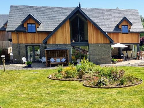 a large wooden house with a lawn in front of it at Solheimir at Strathmore Golf Course in Blairgowrie