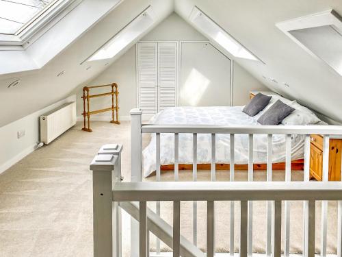 a bedroom with a white bed in a attic at Alma Cottage in Borgue