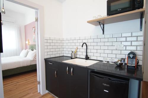 cocina con armarios negros, fregadero y cama en Bruno 55 By Peraia, en Tel Aviv