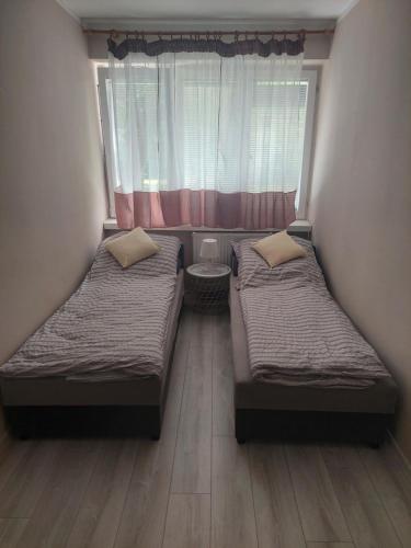 2 camas en una habitación pequeña con ventana en Apartament L14, Mieszkanie dla Wszystkich, en Konin