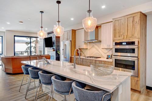 a kitchen with a large island with bar chairs at Downtown WP River Front Villa 242 I Private Hot Tub I Great Views in Winter Park