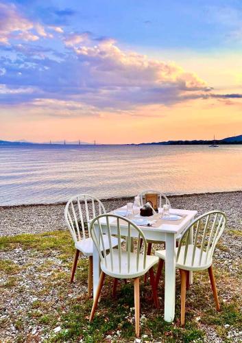 a table and chairs on a beach with the ocean at Costos Condos NEW 10B 2 Bedrooms Condo in Nafpaktos