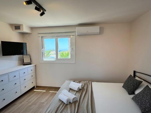 a bedroom with a bed and a tv and a window at Osservatorio House in Laganas
