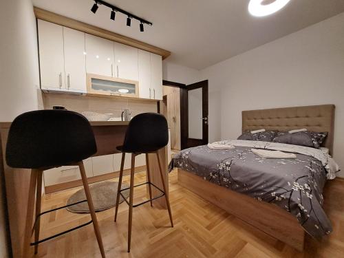 ein Schlafzimmer mit einem Bett und zwei schwarzen Barhockern in der Unterkunft Apartman Imperator Vrnjačka Banja in Vrnjačka Banja