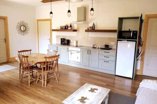 La cuisine est équipée d'une table, de chaises et d'un réfrigérateur. dans l'établissement Spacious villa apartment with mountain view -2 bed, à Quillan