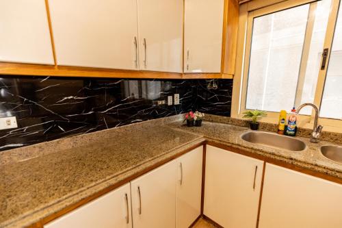 a kitchen with white cabinets and a sink and a window at Modern Luxe Oak Orchid 3BR Apt W-Free WiFi &Parking in Cairo
