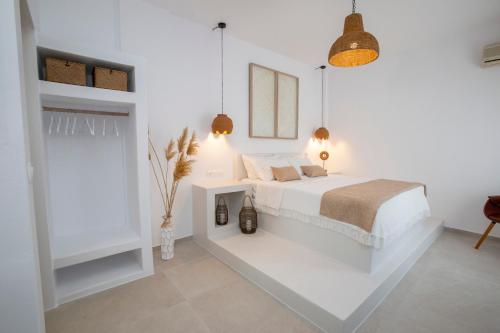a white bedroom with a bed and a table at studio lefkes kea in Vourkari