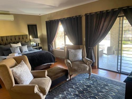 a bedroom with a bed and a couch and chairs at Zacks Country Stay Self-catering in Krugersdorp