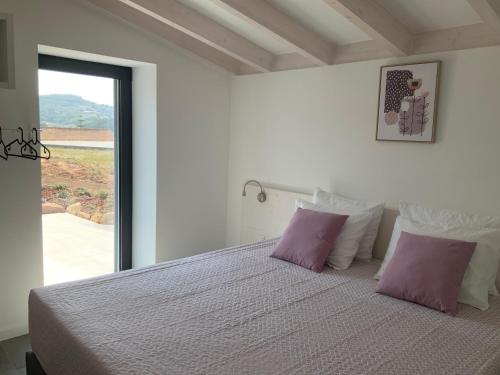 a bedroom with a bed with purple pillows and a window at Quinta da Ema 