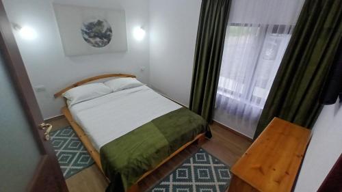 a small bedroom with a bed and a window at Chalet Alina in Borşa