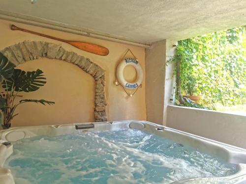 a bath tub in a room with a window at Le Cellier de Beaulieu, au pied de la Cité, Maison de Vacances avec Climatisation et Jacuzzi in Carcassonne