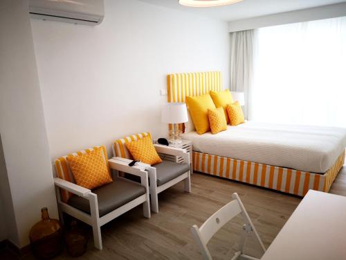 a bedroom with a bed and two chairs and a window at Hotel HS Milfontes Beach - Duna Parque Group in Vila Nova de Milfontes