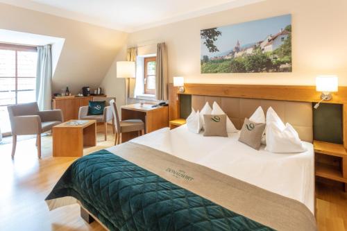 ein Hotelzimmer mit einem Bett und einem Wohnzimmer in der Unterkunft Donauwirt - Hotel garni in Weissenkirchen in der Wachau