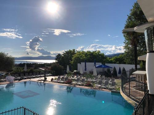 une grande piscine avec des chaises longues et le soleil dans l'établissement Appartamenti Montefelice, à Bardolino