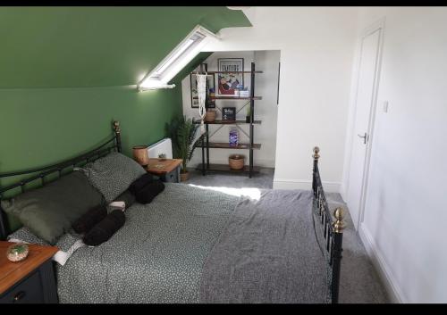 um quarto com uma cama e uma parede verde em Penthouse suite, Victoria Apartments em Prestatyn