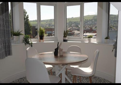 una mesa y sillas en una habitación con ventanas en Penthouse suite, Victoria Apartments, en Prestatyn