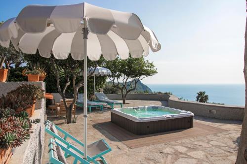 a patio with an umbrella and a hot tub at Villa Titina - Sunset Apartments in Ischia