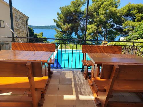 une terrasse avec tables et bancs en bois et vue sur l'eau dans l'établissement Villa Penava, private beach, pool and 7min to Trogir, à Trogir