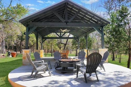 a pavilion with chairs and a table in a yard at Fox Hollow - Tiny home with Cypress Creek access, park like setting in Wimberley