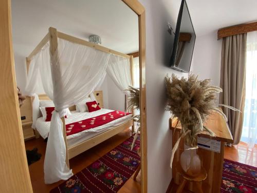 a bedroom with a canopy bed and a mirror at Paradisul Verde in Jurilovca