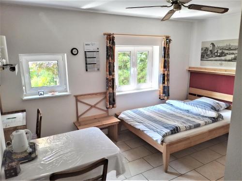 a bedroom with a bed and a table and two windows at Highland Accommodation Bavaria in Weilheim in Oberbayern