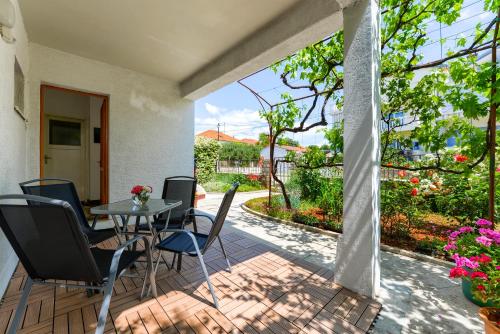 - une terrasse avec une table, des chaises et des fleurs dans l'établissement Apartman Klarin, à Zadar