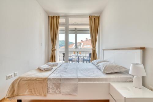 a white bedroom with a large bed and a window at Sigma apartment in Budva