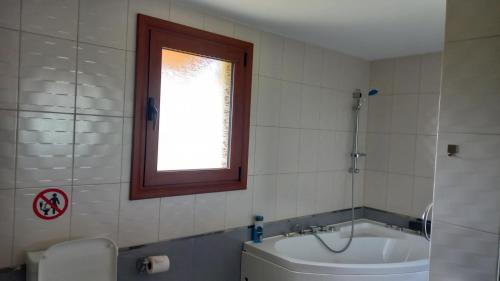 baño con bañera, aseo y ventana en Villa MARGIANI, en Chalkida