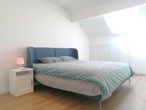 a bedroom with a blue bed and a nightstand with a lamp at La Maison Heureuse in Châtelet