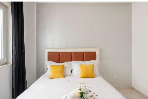 a bedroom with a white bed with yellow pillows at Appartement 23 Ensoleillé à 5min de la Plage Piscine à 15km de l'appartement in El Jadida