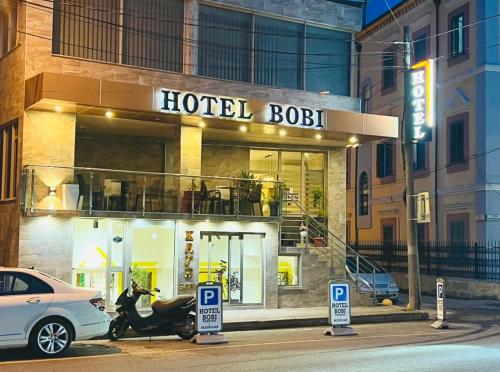 un edificio de hotel con una motocicleta estacionada frente a él en Bobi Hotel, en Shkodër