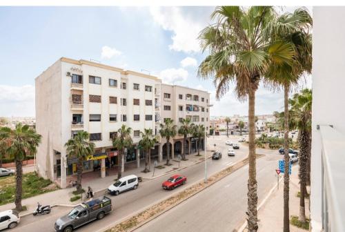 a street with palm trees and cars on a city street at Appartement 23 Ensoleillé à 5min de la Plage Piscine à 15km de l'appartement in El Jadida