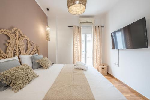 a bedroom with a large white bed with a flat screen tv at Nomad Pennie Home by CloudKeys in Athens