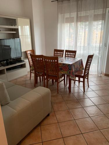 un soggiorno con tavolo, sedie e divano di CASA AURORA a Porto Santo Stefano