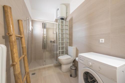 een badkamer met een toilet, een douche en een wasmachine bij Nomad Pennie Home by CloudKeys in Athene