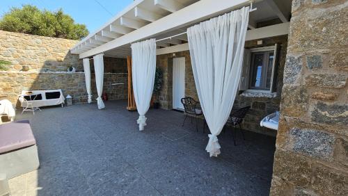 a patio with white curtains and chairs on a building at Mykonos Double Luxury Mini Suites-With External Hot spa Adults only in Ano Mera