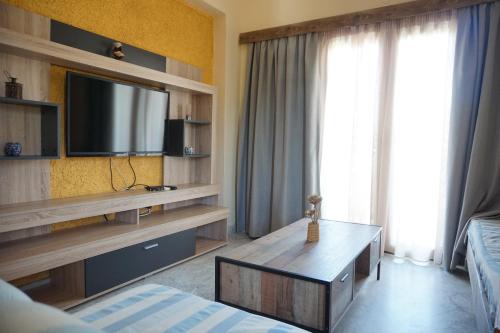 salon z telewizorem, łóżkiem i stołem w obiekcie Katerini Apartments Hotel w mieście Platanes