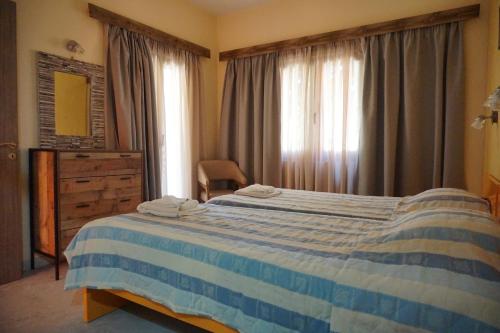 a bedroom with a blue and white bed and a window at Katerini Apartments Hotel in Platanes