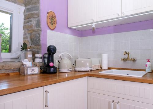 a kitchen with white cabinets and purple walls at Lavanderin Apartment in Dekani