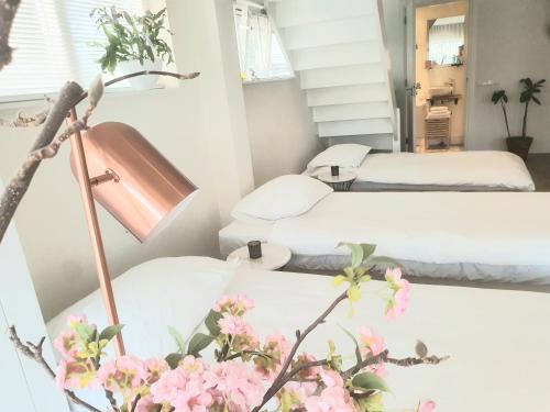 a room with two beds and a lamp and flowers at Luxury loft at lake Volendam 20 min. from Amsterdam CS in Volendam