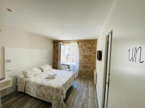 - une chambre avec un lit et un mur en briques dans l'établissement Hospedaje CasaSampedro, à Muros