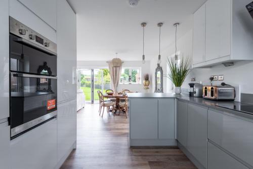 a kitchen with white cabinets and a dining room at Luxuriously appointed 3 bedroom cottage off road parking for 3 vehicles dogs welcome by prior arrangement only 3 church cottages Alfrick close to Malvern and Worcester and Shelsley Walsh in a lovely village close to M5 Dogs welcome in Great Malvern