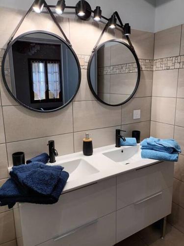 une salle de bain avec un lavabo et deux miroirs dans l'établissement GÎTE AUX VIEUX BOIS, à Lunas