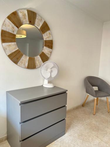 a mirror above a dresser with a lamp and a chair at Alojamento Ramos in Quarteira